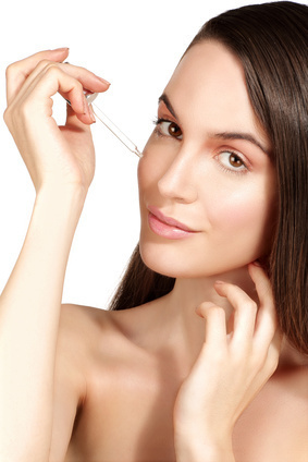 Beautiful model applying a cosmetic skin serum treatment